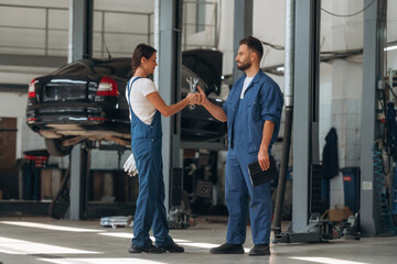 Fototapeta premium Auto repair shop employees are working together. Man and woman