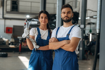 Tools in hand. Auto repair shop employees are working together. Man and woman