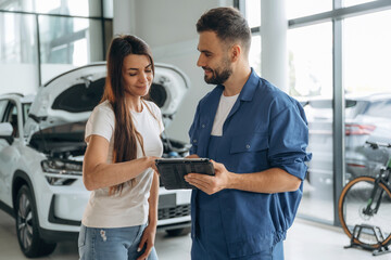 Giving the consultation. Woman customer is in the car repair service station with mechanic