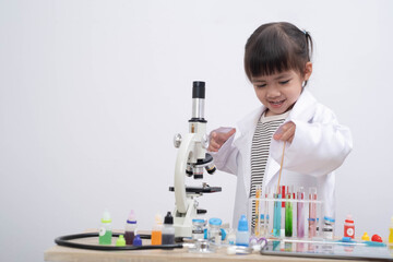 A young child wearing a lab coat explores colorful test tubes and a microscope, showcasing early science learning, creativity, and STEM education in a fun laboratory environment.