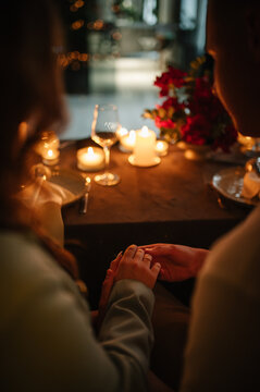 Romantic date by candlelight at night in restaurant. Hands man holds woman's hand. Couple in love. Dinner set up table. Valentine's Day evening, burning candles for surprise marriage proposal.