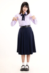 Happy pretty Asian student girl in school uniform pointing finger isolated on white background.