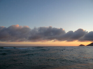 Obraz premium Scenic ocean sunset with clouds and distant hills