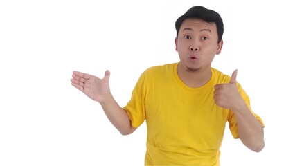 smiling happy Asian man imaginary holding something on hand and pointing it for advertising. Asian man wearing a yellow t-shirt pointing at something he holds. indonesian man showing something on hand