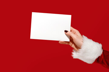 Womans hand in Santa sleeve holding blank card on red background. Christmas mockup