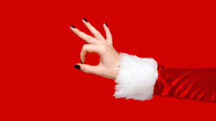 Santa-style hand showing OK gesture on red background. Creative seasonal messaging.