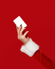 Womans hand in Santa sleeve holding blank card on red background. Christmas mockup.