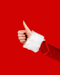 A womans hand dressed in a red Santa Claus sleeve is shown making a thumbs-up gesture against a bright red background.