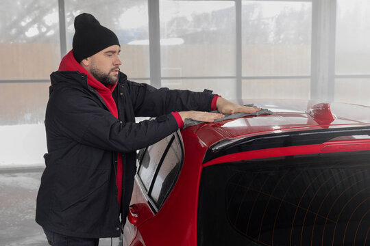 Man in self-service car wash wipes car with rag, dries