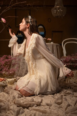 Woman in a vintage dress touching a rose in a romantic floral setting