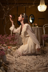 Woman in a vintage dress touching a rose in a romantic floral setting