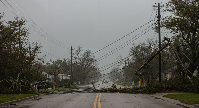 Downed power lines and fallen trees on deserted road after storm  
