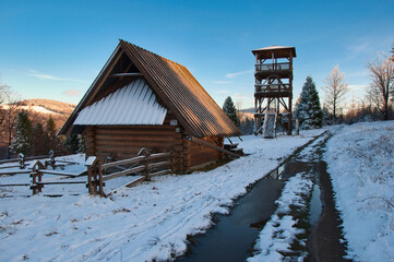 Górski zimowy szlak z turystyczną chatą i wieżą widokową z widokiem na mroźny las o zachodzie słońca. Zimowy szlak na Stary Groń w Beskidzie Śląskim. © Pol Badger