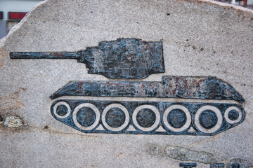 Grawerowany emblemat czołgu na kamiennym pomniku symbolizującym historię wojny i siłę militarną. © Pol Badger