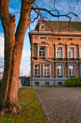 Elegancki zabytkowy pałac z okazałym wejściem, drzewami i brukowaną aleją w otoczeniu parku. Pałac Pogrzebień – neorenesansowy pałac z XIX wieku. © Pol Badger