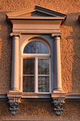 Okno architektoniczne z klasycznymi kolumnami i ozdobnym gzymsem w świetle zachodzącego słońca. © Pol Badger