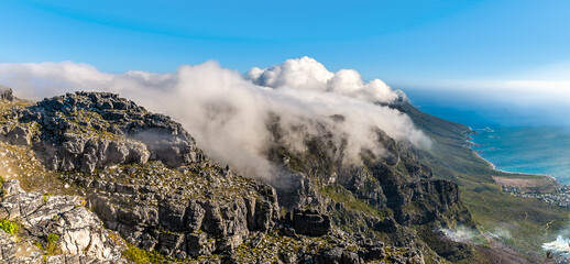A panorama view of clouds coming over the Twelve Apostles mountain range from the summit of Table mountain, South Africa in springtime