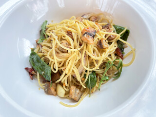 Spaghetti with sauteed garlic, basil and crispy fish pieces, warm savory aroma and rustic plating