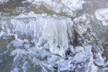 Close-up view of intricate ice formations on a water surface, showcasing bubbles and textured patterns, creating a captivating winter scene filled with natural beauty and detail