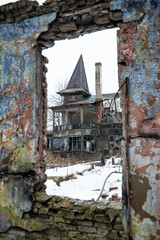Abandoned tower house stands in ruins, framed by a decayed wall