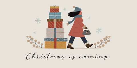 A woman carrying a stack of christmas gifts walks in winter