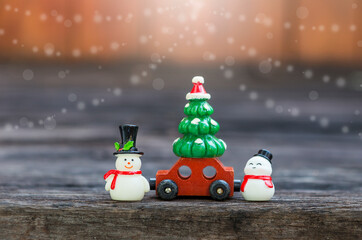 Happy snowman with Christmas tree on red toy car over blurred background, Christmas card background...