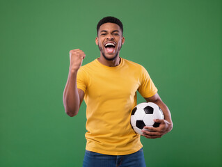 Excited man celebrating soccer goal holding football