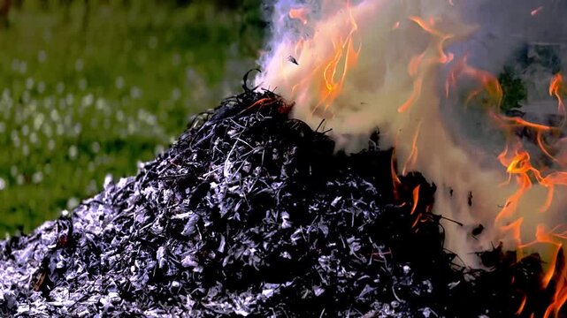 dangerously hot orange and red flames with dense black smoke consuming wood and embers