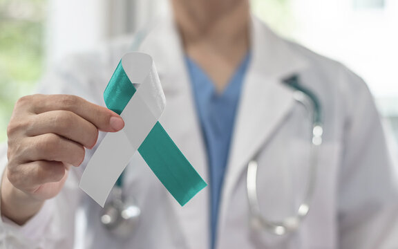 Teal and white ribbon for cervical cancer awareness month in January and HPV prevention with bow on medical doctor's hand support