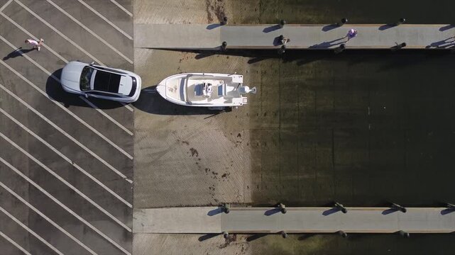 Aerial view of suv launching small boat on trailer in the water at the marina