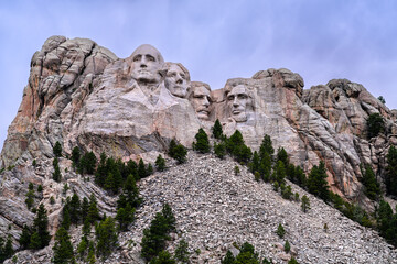 Mount Rushmore National Memorial features carved presidents faces in granite. Iconic sculpture stands above pine forest and talus slope in Black Hills of South Dakota, USA