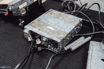 Old car stereo head units (radios or cassette decks) on a workbench in an auto service garage. Repair, diagnostics, and maintenance of vintage automotive audio equipment.
