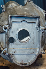 Disassembled old car gearbox with gears and tools on a workbench in an auto service garage. Repair, maintenance, and replacement of worn mechanical transmission parts in a vehicle.