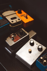 Collection of guitar effect pedals on a dark pedalboard background. Analog musical equipment for electric guitar. Colorful stompboxes with knobs for rock music and professional studio sound recording.