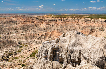 Pinnacles Overlook features eroded rock formations in Badlands National Park, South Dakota, USA. Scenic landscape shows sedimentary layers and canyons under blue sky