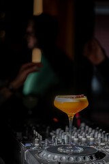 A Porn Star Martini cocktail on a professional DJ mixer in a dark bar, capturing a vibrant nightlife and party atmosphere.