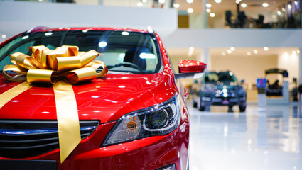 Red car with gold ribbon in car showroom highlighting new vehicle promotion, special offer, electric car sale, gift concept and dealership advertisements. new vehicle purchase