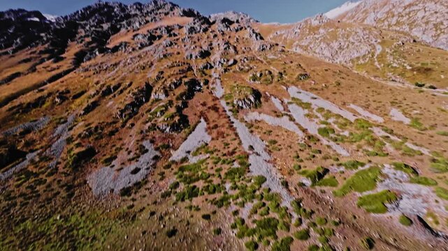 Aerial view of a FPV UAV pursuing high in the mountains on a sunny day. Tracking and pursuing a self-assembled drone.