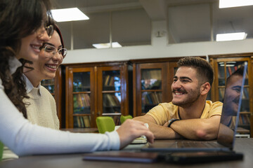 Group of college students studying together in the library reading area