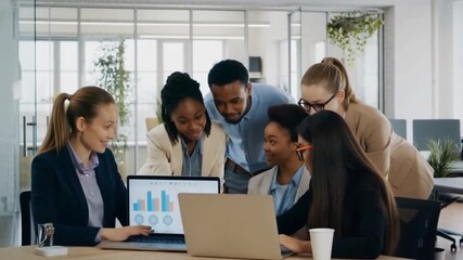 A diverse group of colleagues collaborating and working together in a modern office, reviewing data on a laptop Stock Video - Powered by Adobe