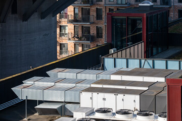 This image captures a rooftop scene featuring various industrial units with an urban backdrop, showcasing a blend of architectural and industrial elements in modern cities.