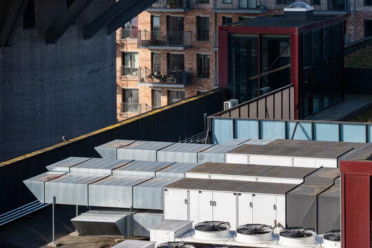 This image captures a rooftop scene featuring various industrial units with an urban backdrop, showcasing a blend of architectural and industrial elements in modern cities.