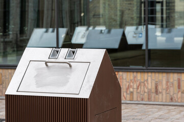 A modern and stylish public waste bin showcases a unique design while reflecting its surroundings, emphasizing functional artistry in urban spaces through innovative design.