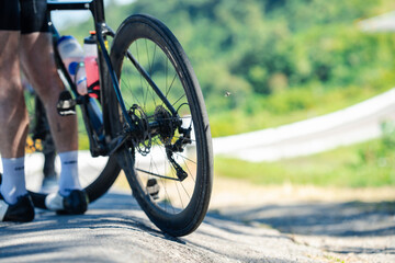 A cyclist pauses on a scenic road, showcasing the bike's rear wheel against a lush green backdrop.