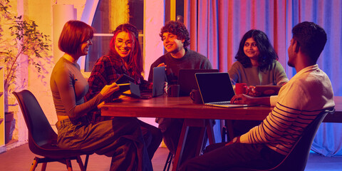 Team meeting with diverse colleagues collaborating at wooden table. Concept of teamwork, digital workflow, corporate communication, startup culture, and creative problem-solving in modern offices.