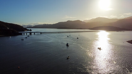 Aerial view across the Barmouth estuary with boats and mountains in morning light