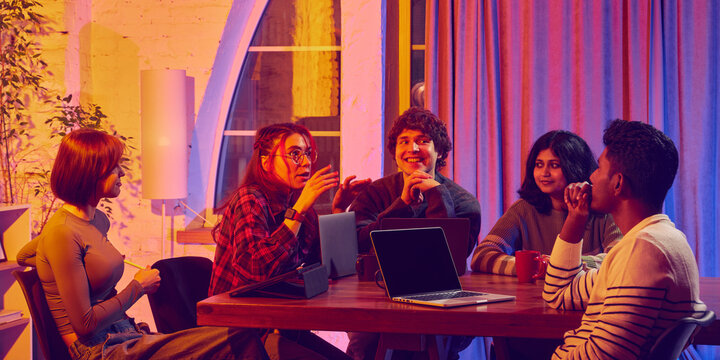 Group collaborating with diverse tech devices during creative meeting. Concept of teamwork, digital tools, startup innovation, inclusive communication, and collaborative idea development.