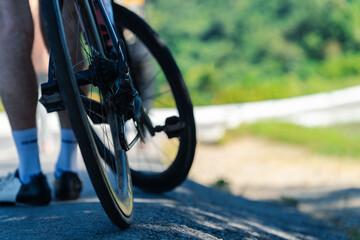 A close-up view of a bicycle wheel on a road, capturing the motion and outdoor setting, with greenery blurred in the background.