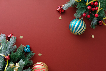 Simple Christmas flat lay with corner arrangement of frosted pine, ornaments, and gold stars on red.