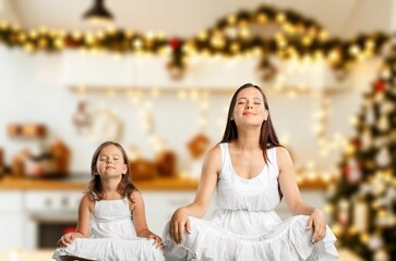 Naklejka premium Healthy mother and girl doing yoga at christmas morning